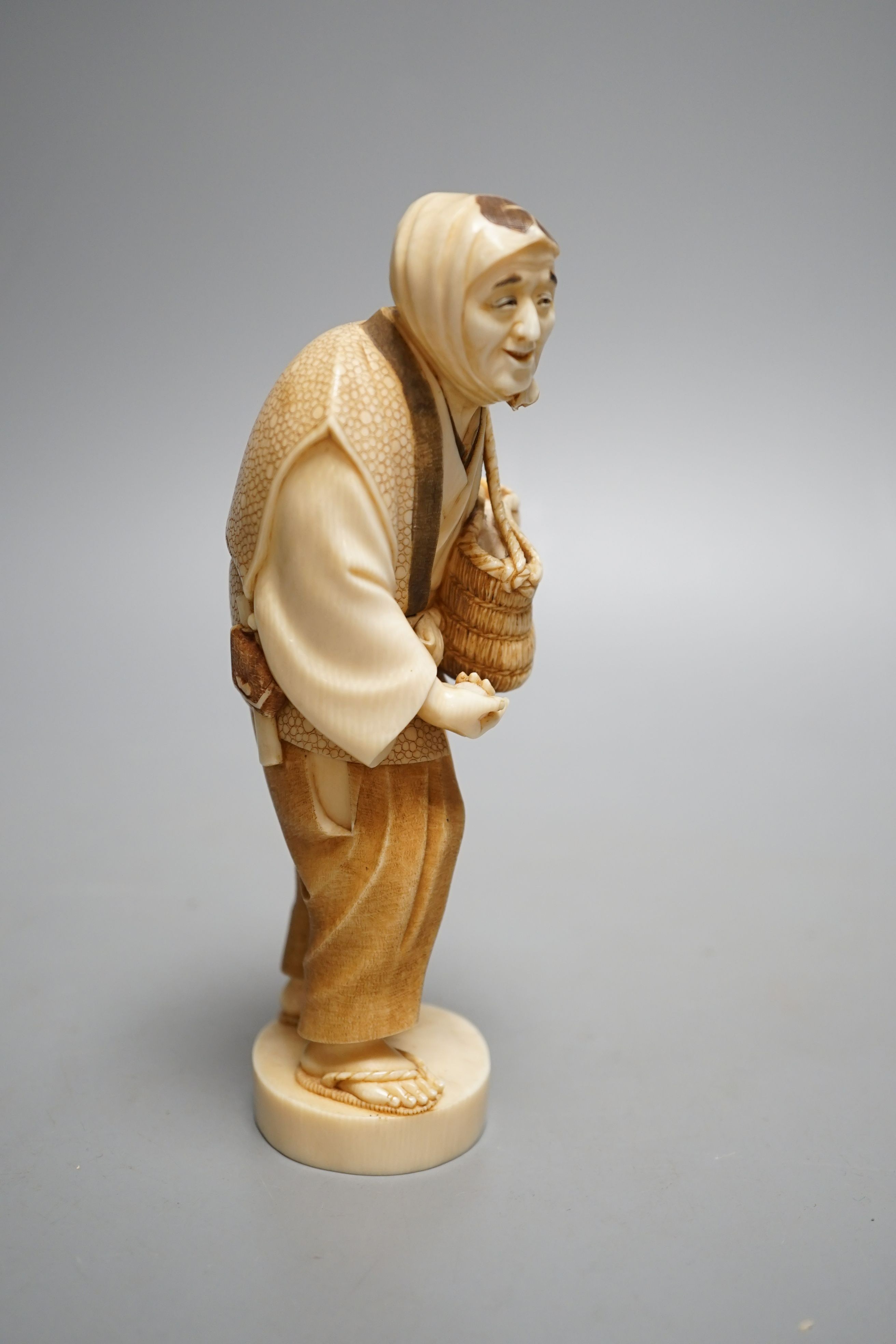 A Japanese ivory figure of a peasant farmer, Taisho/early Showa period, signed to a lacquer tablet - 17cm tall